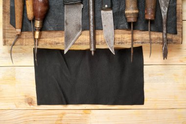 Deri el sanatları araçları ahşap arka plan üzerinde. Craftmans çalışma masası. Gizle ve el yapımı araçları parçası. Üstten Görünüm