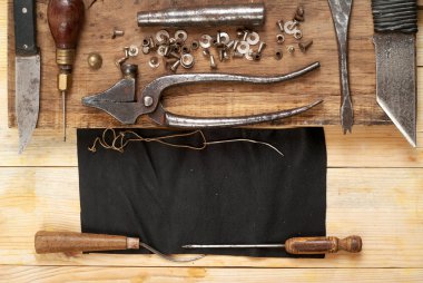 Deri el sanatları araçları ahşap arka plan üzerinde. Craftmans çalışma masası. Gizle ve el yapımı araçları parçası. Üstten Görünüm