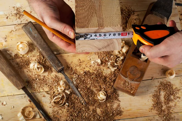 Carpintero trabajando, martillo, medidor y destornillador sobre fondo de construcción — Foto de Stock