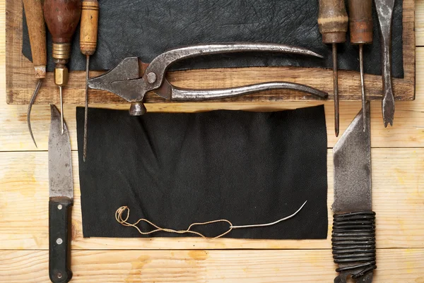 Δέρμα τα σύνεργα της χειροτεχνίας σε ξύλινα φόντο. Craftmans επιφάνεια εργασίας. Κομμάτι απόκρυψη και χειροποίητα εργαλεία. Κάτοψη — Φωτογραφία Αρχείου