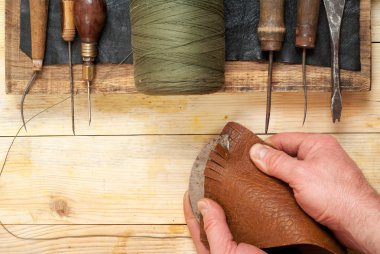 Deri el sanatları araçları ahşap arka plan üzerinde. Craftmans işçiliği DIY araçları kullanarak deri ile çalışma. Çalışma tablosu gizle ve çalışma el yapımı araçları parçası. Uzay kopyalayın. Üstten Görünüm