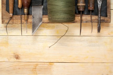 Deri el sanatları araçları ahşap arka plan üzerinde. Craftmans çalışma masası. Gizle ve el yapımı araçları parçası. Üstten Görünüm
