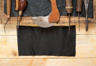 Deri el sanatları araçları ahşap arka plan üzerinde. Craftmans çalışma masası. Gizle ve el yapımı araçları parçası. Üstten Görünüm