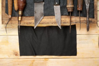 Deri el sanatları araçları ahşap arka plan üzerinde. Craftmans çalışma masası. Gizle ve el yapımı araçları parçası. Üstten Görünüm