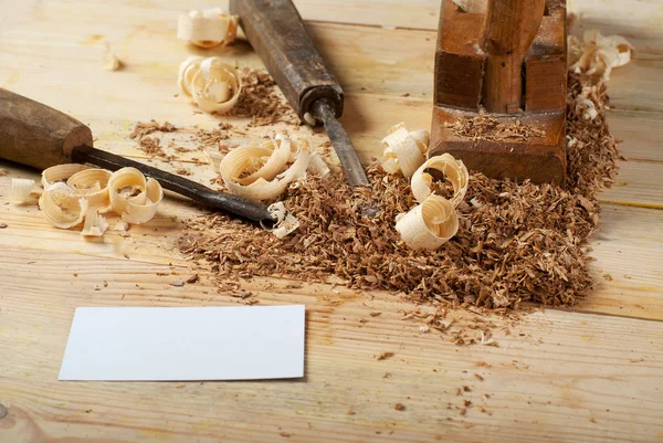 Business card on wooden table for carpenter tools with sawdust.