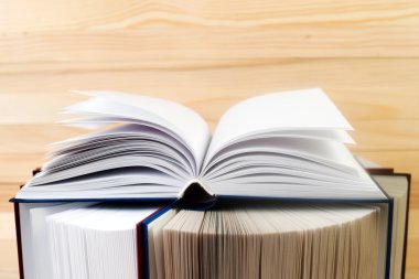 Açık kitap, ahşap masa üzerinde ciltli kitap yığını. Okula dönüş. Kopya alanı