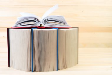 Açık kitap, ahşap masa üzerinde ciltli kitap yığını. Scho için