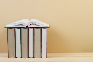 Açık kitap, ahşap masa üzerinde ciltli kitap yığını. Okula dönüş. Kopya alanı