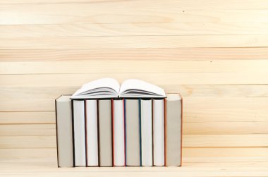 Açık kitap, ahşap masa üzerinde ciltli kitap yığını. Okula dönüş. Kopya alanı