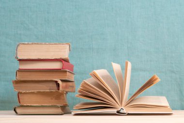 Açık kitap, ahşap masa üzerinde ciltli kitap yığını. Okula dönüş. Kopya alanı