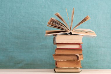 Açık kitap, ahşap masa üzerinde ciltli kitap yığını. Okula dönüş. Kopya alanı