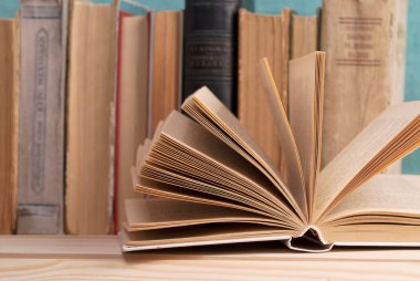 Açık kitap, ahşap masa üzerinde ciltli kitap yığını. Okula dönüş. Kopya alanı