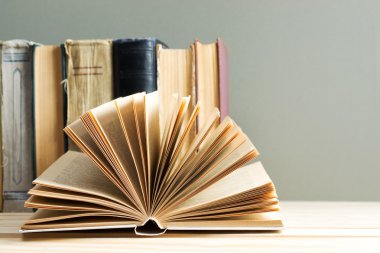 Açık kitap, ahşap masa üzerinde ciltli kitap yığını. Okula dönüş. Kopya alanı