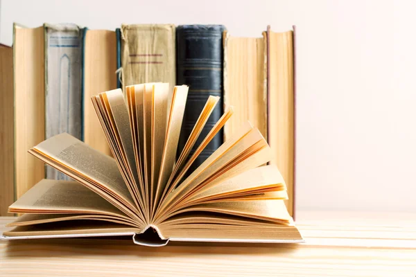 Açık kitap, ahşap masa üzerinde ciltli kitap yığını. Okula dönüş. Kopya alanı