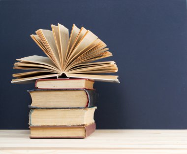 Açık kitap, ahşap masa üzerinde ciltli kitap yığını. Okula dönüş. Kopya alanı