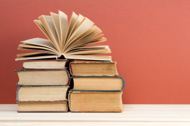 Açık kitap, ahşap masa üzerinde ciltli kitap yığını. Okula dönüş. Kopya alanı