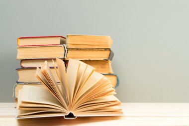 Açık kitap, ahşap masa üzerinde ciltli kitap yığını. Okula dönüş. Kopya alanı