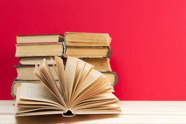 Açık kitap, ahşap masa üzerinde ciltli kitap yığını. Okula dönüş. Kopya alanı