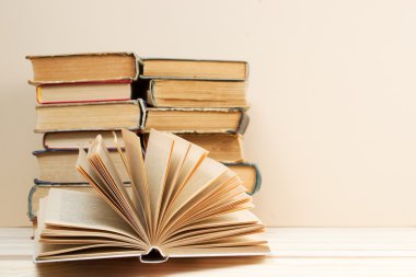 Açık kitap, ahşap masa üzerinde ciltli kitap yığını. Okula dönüş. Uzay kopyalayın. Üstten Görünüm