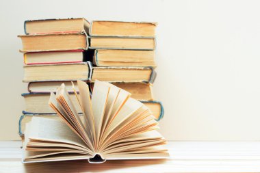 Açık kitap, ahşap masa üzerinde ciltli kitap yığını. Okula dönüş. Kopya alanı
