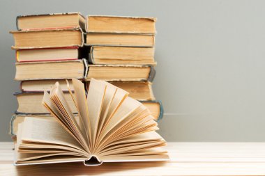 Açık kitap, ahşap masa üzerinde ciltli kitap yığını. Okula dönüş. Kopya alanı
