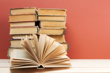 Açık kitap, ahşap masa üzerinde ciltli kitap yığını. Okula dönüş. Kopya alanı