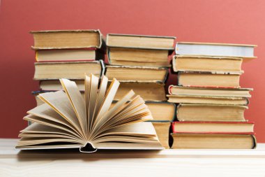 Açık kitap, ahşap masa üzerinde ciltli kitap yığını. Okula dönüş. Kopya alanı