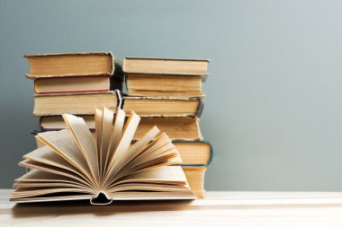 Açık kitap, ahşap masa üzerinde ciltli kitap yığını. Okula dönüş. Kopya alanı