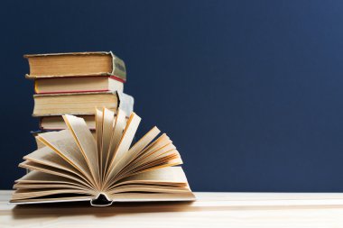 Açık kitap, ahşap masa üzerinde ciltli kitap yığını. Okula dönüş. Kopya alanı