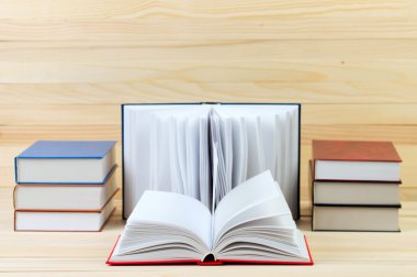 Açık kitap, ahşap masa üzerinde ciltli kitap yığını. Scho için