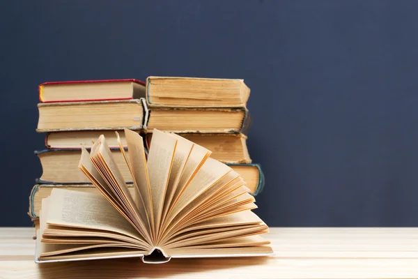 Open book, stack of hardback books on wooden table. Back to school. Copy space — Stock Photo, Image