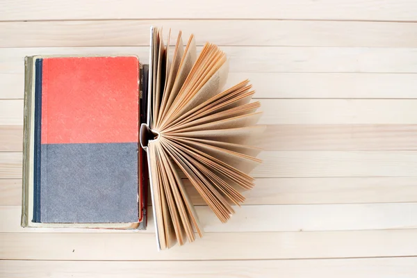 Açık kitap, ahşap masa üzerinde ciltli kitap yığını. Okula dönüş. Uzay kopyalayın. Üstten Görünüm — Stok fotoğraf