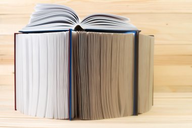 Açık kitap, ahşap masa üzerinde ciltli kitap yığını. Okula dönüş. Kopya alanı