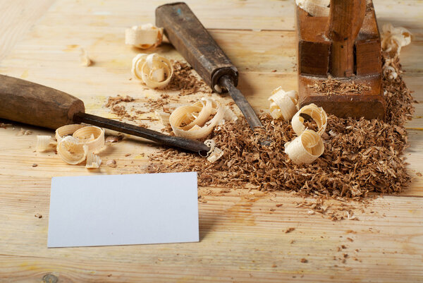 Business card on wooden table for carpenter tools with sawdust.