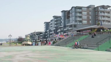 Point Ruston Tacoma WA 5 Ekim 2025 körfez yakınlarındaki bir meydanda tatilciler. Arka planda konut binaları var.