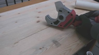 Pille çalışan bir boru kesicisiyle plastik bir boruyu kesmek.