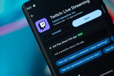 Dhaka, Bangladeş 07 Aralık 2025: Twitch logosu bir akıllı telefon ekranında görüntülenirken, Twitch web sitesi arka planda bir bilgisayar ekranında görünür.