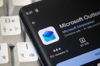 Dhaka, Bangladeş 26 Aralık 2025: Mikrosoft görünüm logosu bir akıllı telefon ekranında sergilenmektedir, arkaplanda bir bilgisayar ekranında bir stok grafik web sayfası görünür.