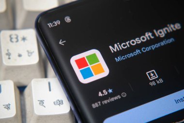 Dhaka, Bangladeş 26 Aralık 2025::: Ekranda Microsoft Ignite uygulamasını kulaklıkla mavi bir üste gösteren telefon