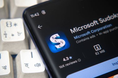 Dhaka, Bangladeş 26 Aralık 2025::: Microsoft Sudoku uygulamasını yanında kulaklıklar ile yükleme sayfasında gösteren akıllı telefon