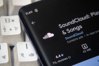 Dhaka, Bangladeş 07 Aralık 2025: Soundcloud logosu bir akıllı telefon ekranında gösterilir, arka planda bilgisayar ekranında bir stok grafik web sayfası görünür.