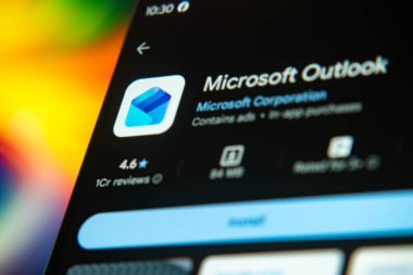 Dhaka, Bangladeş 26 Aralık 2025: Mikrosoft görünüm logosu bir akıllı telefon ekranında sergilenmektedir, arkaplanda bir bilgisayar ekranında bir stok grafik web sayfası görünür.