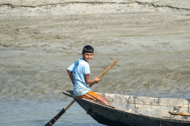 Dhaka, Bangladeş 16 Ocak 2026: Güneşli bir günde teknede kürek çekerken gülümseyen çocuk