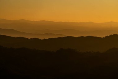Siluetli dağ katmanlarının üzerinde altın gün batımı