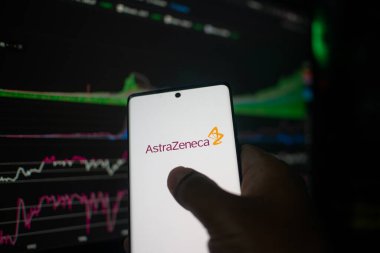 Dhaka, Bangladeş 20 Şubat 2026: AstraZeneca logosunu hisse senedi arkaplanında gösteren el kamerası