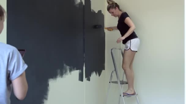 Chica pinta la pared con rodillo de pintura — Vídeos de Stock