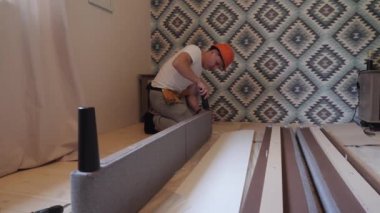 İşçi oturma odasında mobilya topluyor.