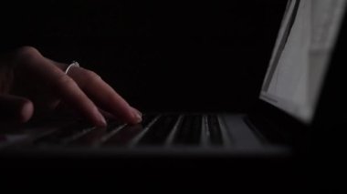 Kadınların elleri karanlıkta dizüstü bilgisayarları kullanır..