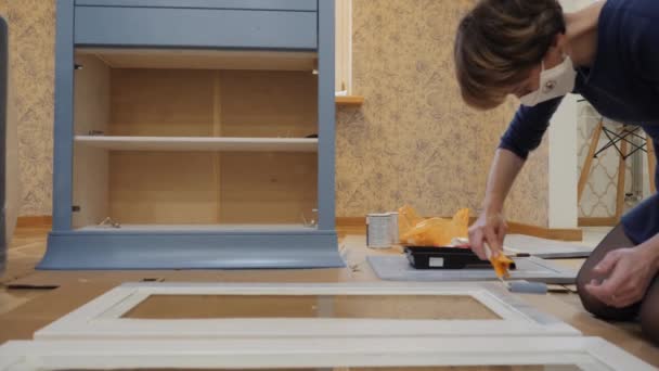 Девушка в самоизоляции перекрашивает мебель дома. — стоковое видео