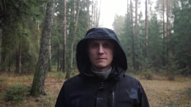 Kafasında başlığı olan ve ormanda dikilen kalın elbiseli bir adamın portresi..